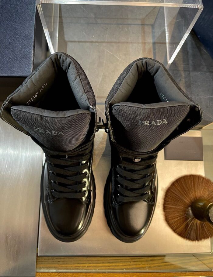 Stivali Prada di lusso in pelle nera, design elegante e dettagli raffinati su tavolo moderno.