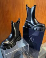 Stivaletti Chelsea neri con suola spessa, design moderno e stile elegante su pedana di plexiglass