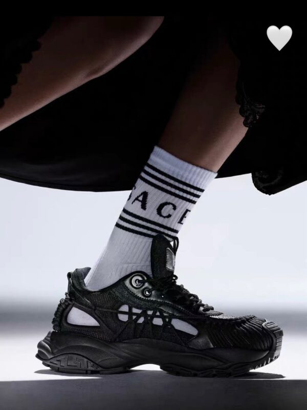 Sneaker nera con calze a strisce bianco e nero, stile urbano e moda contemporanea.