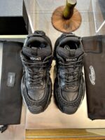 Sneakers Versace di lusso nere con logo, protezioni in tessuto e stile moderno elegante.