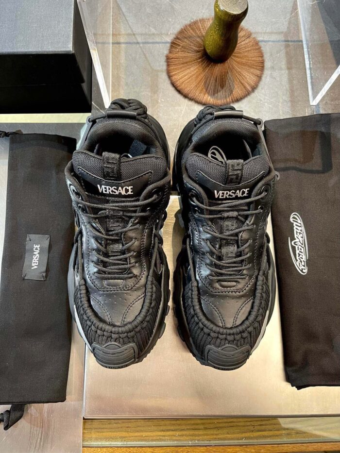 Sneakers Versace di lusso nere con logo, protezioni in tessuto e stile moderno elegante.