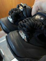 Sneakers nere moderne con lacci voluminosi e dettagli metallici sul tacco.