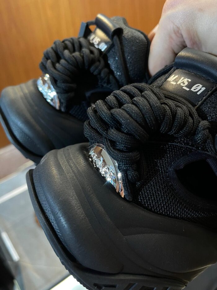 Sneakers nere moderne con lacci voluminosi e dettagli metallici sul tacco.
