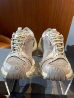 Scarpe da ginnastica beige con suola rugged, design moderno e dettagli pratici per ogni attività.
