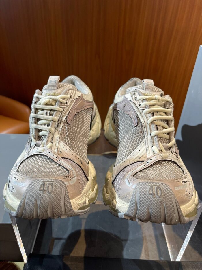 Scarpe da ginnastica beige con suola rugged, design moderno e dettagli pratici per ogni attività.