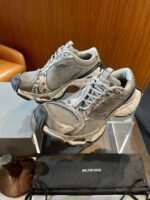 Sneakers Balenciaga di lusso su supporto trasparente in ambiente elegante e moderno.