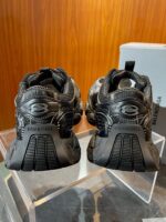 Sneakers Balenciaga nere con design innovativo, su supporto in vetro, stile moderno e di lusso.