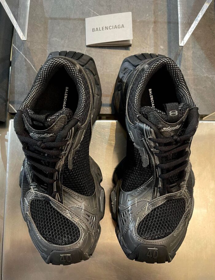 Sneaker Balenciaga nere in showroom moderno, stile sportivo di lusso con design contemporaneo.