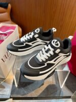 Sneakers nere e bianche di design moderno su supporto trasparente con packaging di lusso.