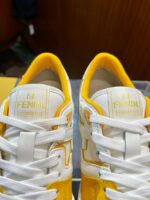 Sneakers Fendi bianche con dettagli gialli e logo dorato, stile elegante e alla moda.