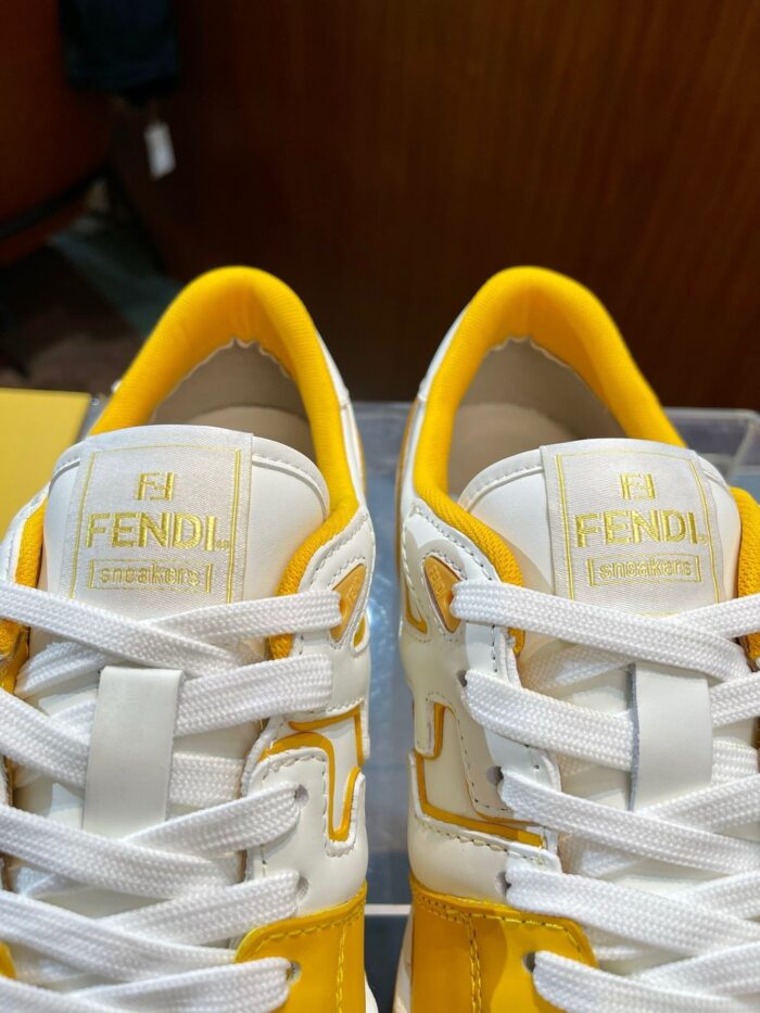 Sneakers Fendi bianche con dettagli gialli e logo dorato, stile elegante e alla moda.