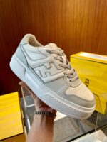 Sneaker uomo grigia con design moderno, su sfondo con scatole di scarpe in negozio.