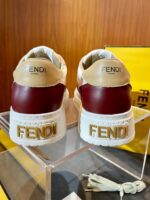 Sneaker Fendi beige e bordeaux con suola spessa e logo dorato, stile elegante e sportivo.