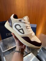 Sneaker elegante beige con dettagli marroni, logo distintivo e design in pelle e suede.