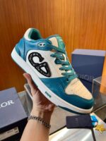 Sneaker Dior in blu teal e bianco, design di lusso con dettagli artigianali e stile moderno.