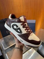 Sneaker di lusso Dior collaboration bianca con dettagli borgogna, logo iconico e design elegante.