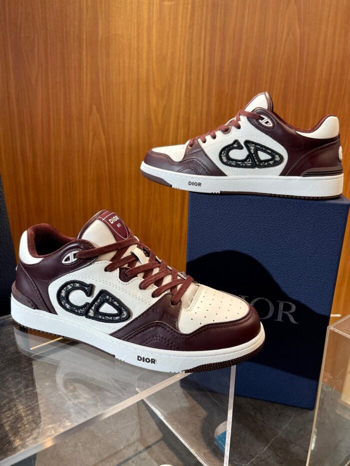 Sneakers Dior bianche e Bordeaux con logo stilizzato su pedana trasparente.