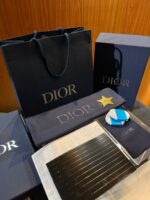 Pacchetti Dior di lusso con scatole, accessori e magazine di moda eleganti.