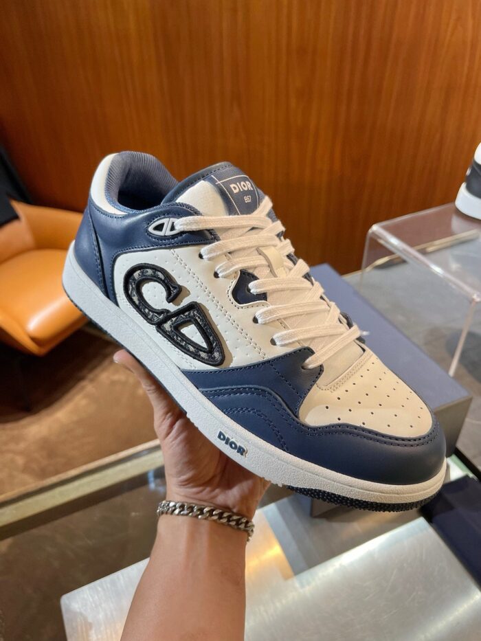 Sneaker moderna in bianco e blu navy con design classico, dettagli perforati e logo distintivo.