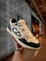 Sneaker Dior beige e nero, design elegante in boutique di alta moda.