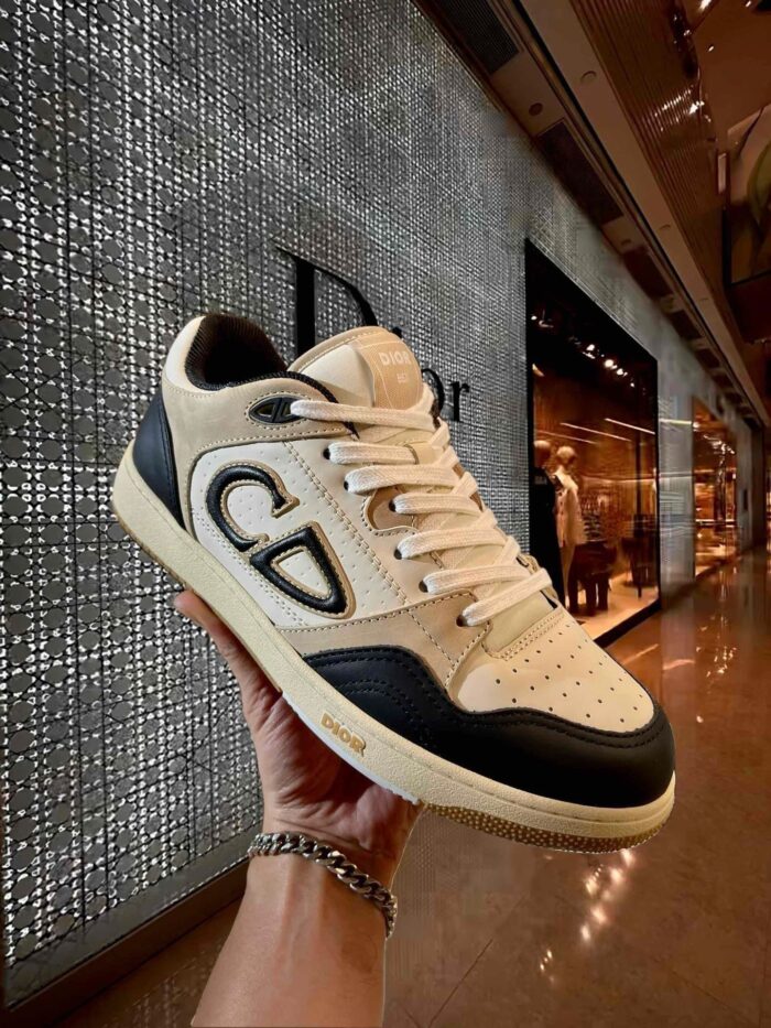 Sneaker Dior beige e nero, design elegante in boutique di alta moda.