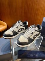 Sneakers di lusso nero e crema su superficie di vetro, stile elegante e moderno.