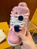 Sneaker rosa di lusso con charms colorati e dettagli moderni, stile streetwear e alta moda.