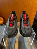 Sneakers Prada nere con dettagli rossi, stile moderno e design di lusso.