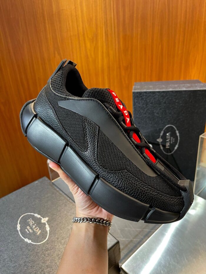 Sneaker nera moderna con dettagli rossi, design innovativo e suola stabile per stile e comfort.
