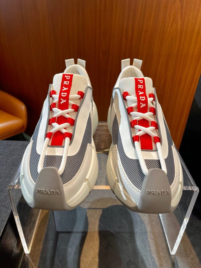 Sneakers Prada moderne sportivo-lusso con dettagli in mesh, pelle e logo, in ambiente elegante.
