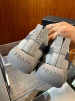 Sneakers Prada in dettagli moderni e di lusso, vista dal retro, su sfondo in legno raffinato.