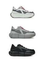 Sneakers moderne bianche, grigie e nere con lacci rossi e suola chunky, stile urbano e versatile.