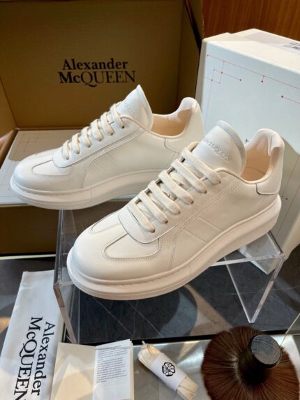 Scarpe sneakers di lusso Alexander McQueen bianche con design moderno e dettagli curati, in esposizione elegante.