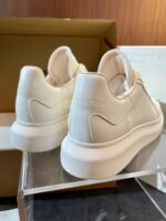 Sneakers bianche in stile minimalista su supporto elegante, perfette per ogni look casual.