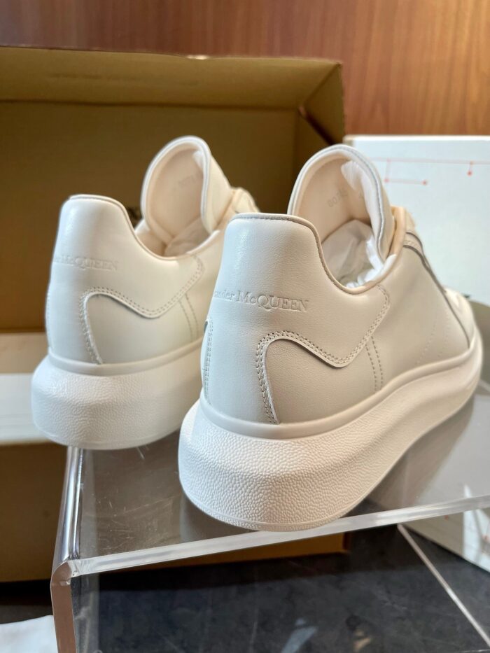 Sneakers bianche in stile minimalista su supporto elegante, perfette per ogni look casual.