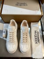 Sneakers Alexander McQueen crema, eleganti e di lusso, con scatola e accessori raffinati.