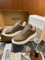 Sneakers di lusso Alexander McQueen in pelle verde-grigia, design elegante e comfort premium.