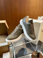 Scarpe sneakers moderne olive e bianco su supporto trasparente, stile minimalista e attenzione ai dettagli.