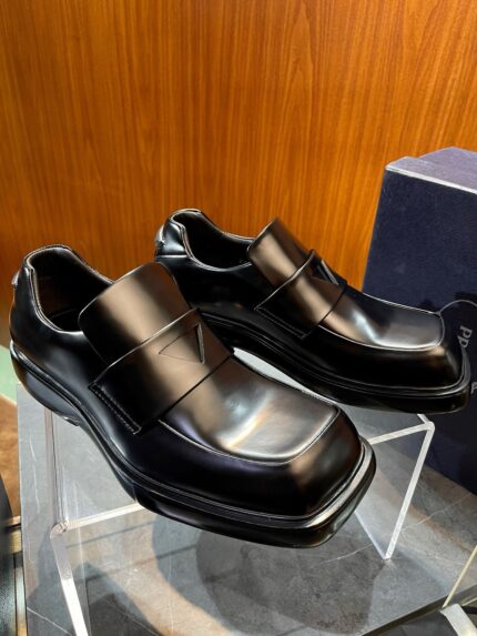 Scarpe eleganti in pelle nera con strap su stand di vetro, stile sofisticato e moderno.