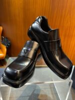 Scarpe eleganti in pelle nere con cinturino, suola rialzata e design moderno.