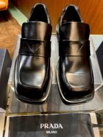 Scarpe Prada Uomo in pelle nera, design moderno, cinturino elegante e logo distintivo.