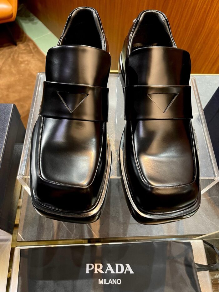 Scarpe Prada Uomo in pelle nera, design moderno, cinturino elegante e logo distintivo.