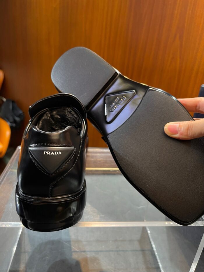 Scarpa Prada in pelle lucida con tacco elegante, design moderno e stile di lusso.