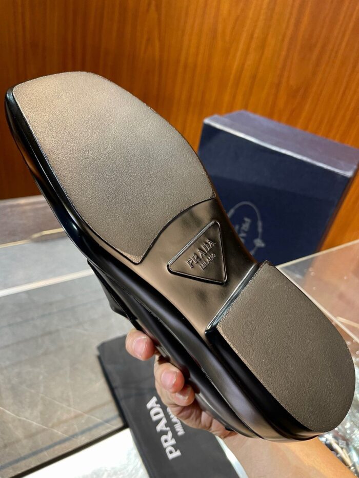 Scarpa Prada di lusso con suola in pelle, logo triangolare e design elegante.