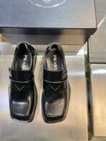 Scarpe nere Prada moderne con cinturino, punta quadrata e design elegante in pelle lucida.