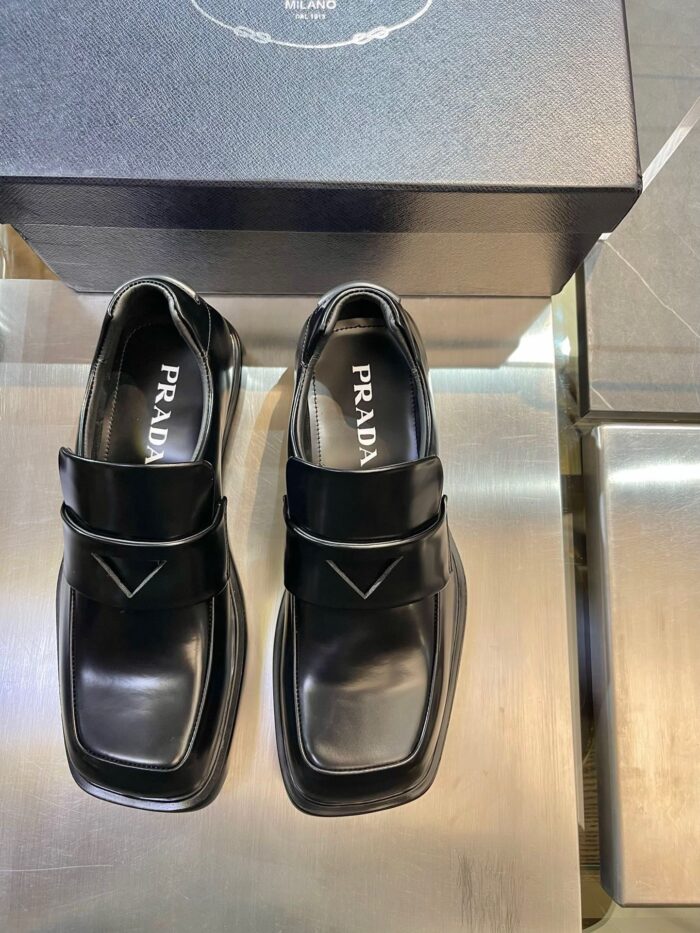 Scarpe nere Prada moderne con cinturino, punta quadrata e design elegante in pelle lucida.