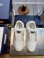Sneakers di lusso bianche con dettagli moderni su superficie in vetro, brand di alta moda.