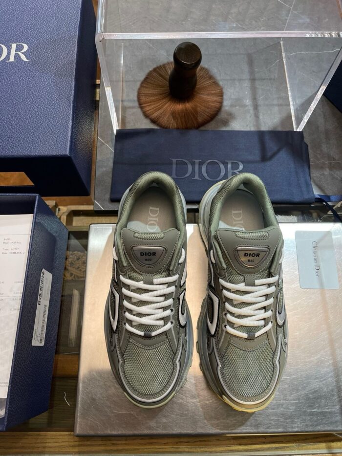 Sneakers Dior di lusso con design elegante, sotto vetro in ambiente esclusivo.