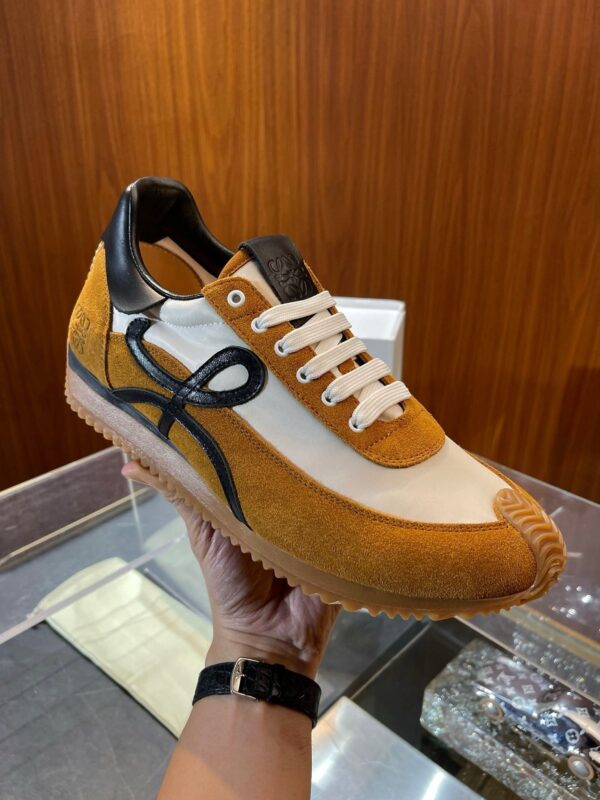 Sneaker moderna bianca e arancione con dettagli neri su sfondo raffinato e riflettente.