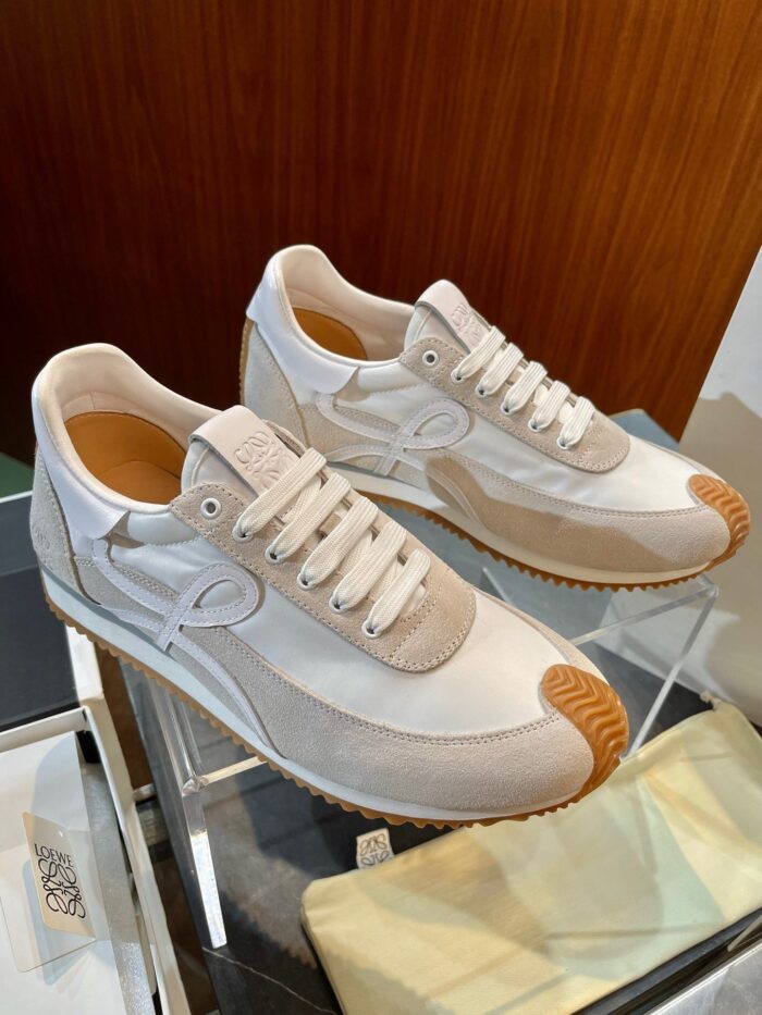 Sneakers bianche minimaliste con suola in gomma vintage e dettagli eleganti, display su sfondo di legno.
